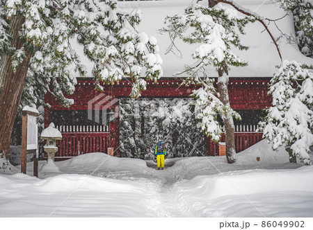 雪景色の神社で一礼する参拝者（鳥居とお参り） 86049902