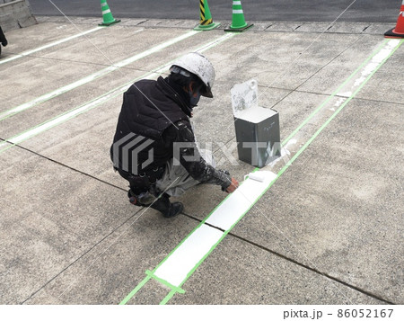 駐車場の区画ラインをローラー塗装で塗り替える男性塗装職人1 86052167