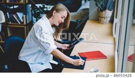 Young woman taking notes from tablet 86053426