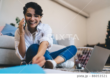 Positive young woman talking on smartphone during work online 86053521