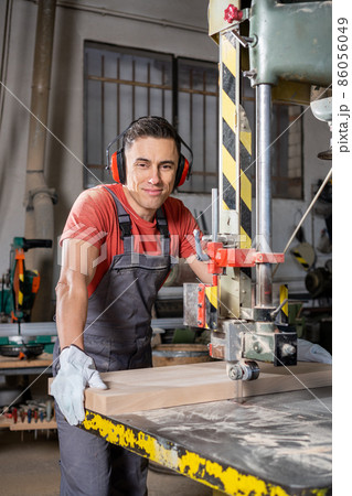 Professional carpenter working at band saw in factory Professional carpenter working at band saw in factory 86056049