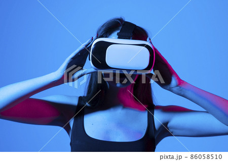 Brunette woman in vr glasses, watching 360 degree video with virtual reality headset illuminated by neon lights. Brunette woman in vr glasses, watching 360 degree video with virtual reality headset illuminated by neon lights. 86058510