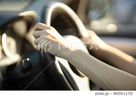 車を運転する若い女性の手元 86061159