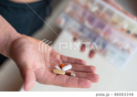 Closeup of a male palm with pills. A man takes a daily dose of vitamins and nutritional supplements from a daily pill box. Closeup of a male palm with pills. A man takes a daily dose of vitamins and nutritional supplements from a daily pill box. 86063348