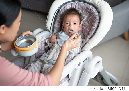 Baby boy being fed in his high chair at home Baby boy being fed in his high chair at home 86064351