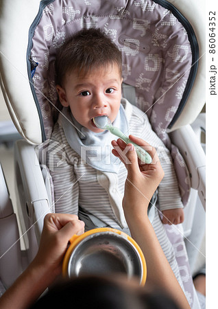 Baby boy being fed in his high chair at home 86064352