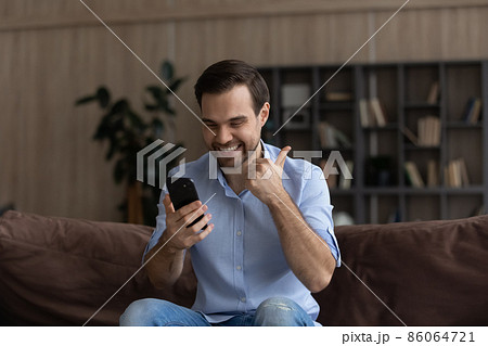 Excited man looking at phone screen, showing thumb up gesture 86064721