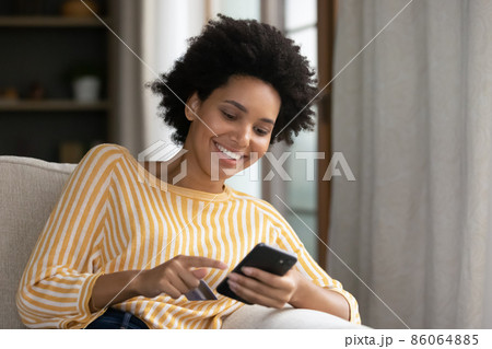 Smiling millennial African American relaxed woman shopping online. Smiling millennial African American relaxed woman shopping online. 86064885