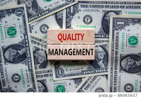 Quality management symbol. Concept words 'Quality management' on wooden blocks on a beautiful background from dollar bills. Business and quality management concept. Quality management symbol. Concept words 'Quality management' on wooden blocks on a beautiful background from dollar bills. Business and quality management concept. 86065637
