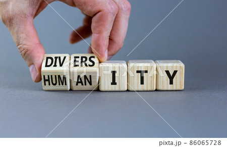 Diversity and humanity symbol. Businessman turns wooden cubes and changes the word 'humanity' to 'diversity'. Beautiful grey background. Business, diversity and humanity concept. Copy space. 86065728