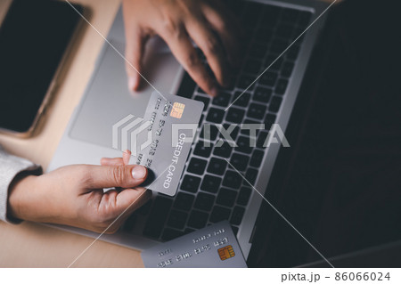Hand holding credit card and using laptop. Businessman or entrepreneur working from home. Online shopping, e-commerce, internet banking, spending money, work from home concept. Internet online banking 86066024