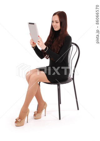Girl sits on a chair and looking at tablet pc 86066570