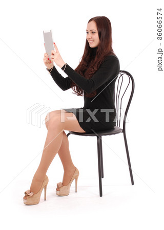 Girl sits on a chair and looking at tablet pc Girl sits on a chair and looking at tablet pc 86066574