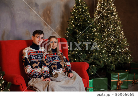 Man and woman sitting on a red sofa and holding a gift 86066669