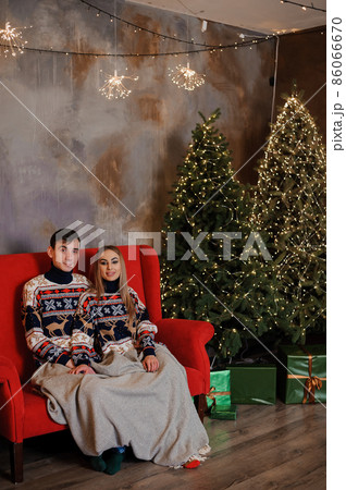 Man and woman sitting on a red sofa and holding a gift 86066670