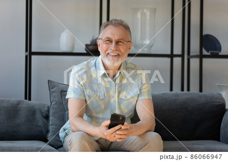 Portrait of smiling old man with cellphone in hands. 86066947