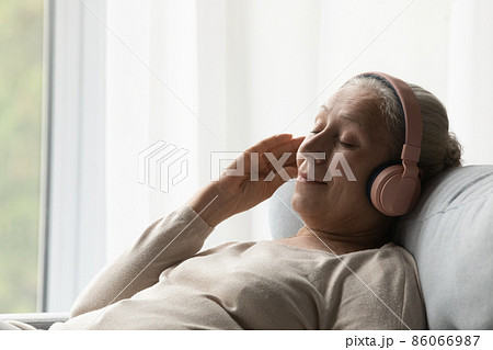 Relaxed middle aged woman listening music in headphones. Relaxed middle aged woman listening music in headphones. 86066987