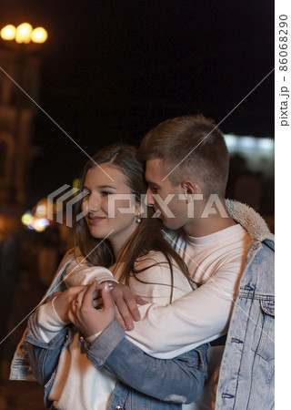 Young couple guy and girl hugging on the background of the night city. Outdoors relationship. Vertical frame 86068290