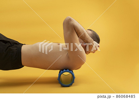 Sport man using myofascial roller for muscle and fascia stretching back. Handsome man doing exercises with foam roller. Side view 86068485