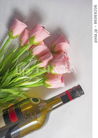Valentine's Day background. Wine bottle with bouquet of pink roses on isolated white background. Top view Valentine's Day background. Wine bottle with bouquet of pink roses on isolated white background. Top view 86069206