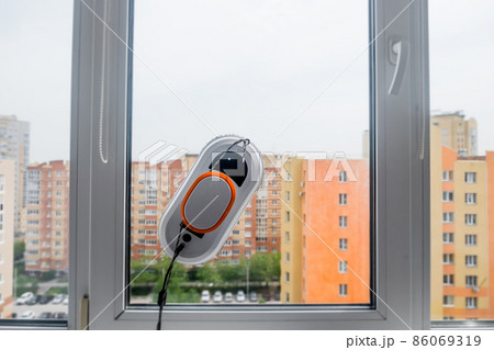 Robot window cleaner work on dirty window. Cleaning the house with smart devices. Automatic vacuum robots for cleaning windows, an assistant for the home 86069319