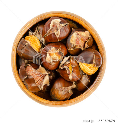 Freshly roasted chestnuts, in a wooden bowl. Popular autumn and winter street food in East Asia, Europe, and New York City. European sweet chestnuts, Castanea sativa, ready to eat roasted in the oven. 86069879