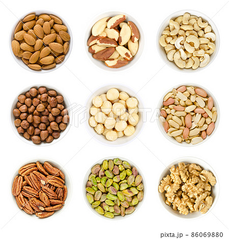 Nine different kinds of nuts in white bowls, isolated on white background. Almond kernels, brazil nuts, cashews, hazelnuts, macadamia nuts, peanuts, pecans, pistachio kernels, and walnut halves. Photo 86069880