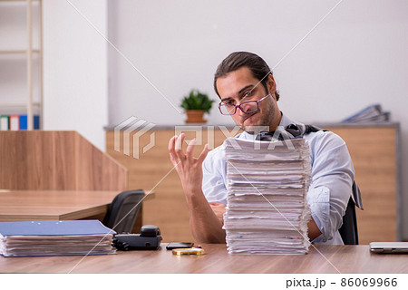 Young male employee unhappy with excessive work in the office 86069966