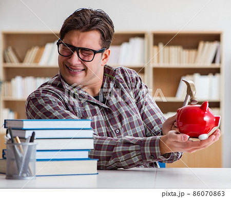 Student breaking piggybank to pay for tuition fees 86070863