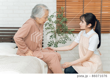 痛がる高齢者女性とエプロン姿の女性(股関節) 痛がる高齢者女性とエプロン姿の女性(股関節) 86071076