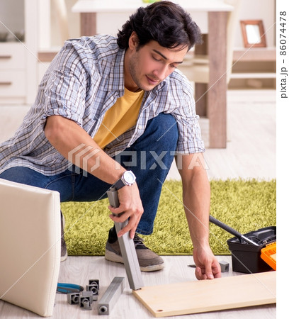 The young handsome man repairing chair at home The young handsome man repairing chair at home 86074478