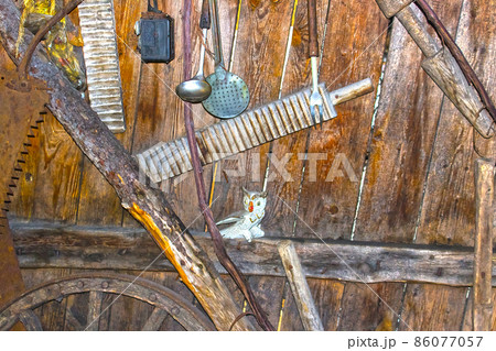 Different kind of vintage old kitchen utensils hung on wooden shelf in kitchen Different kind of vintage old kitchen utensils hung on wooden shelf in kitchen 86077057