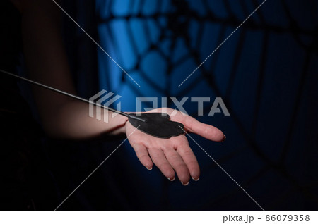 An unrecognizable woman demonstrates an elegant thin leather strip whip in a dark bedroom. Close-up of female hands with a bdsm toy. Pain and pleasure.Adult toy for slaps. 86079358