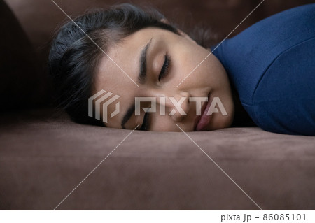 Exhausted young Indian woman sleeping on couch. Exhausted young Indian woman sleeping on couch. 86085101