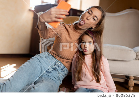 Portrait of smiling mom and daughter taking selfie using smartphone Portrait of smiling mom and daughter taking selfie using smartphone 86085278