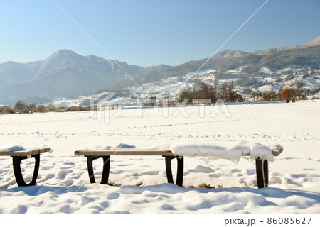河川敷のグラウンドのベンチ越しの冬景色 86085627