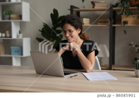 Smiling attractive millennial woman working on computer at home office. Smiling attractive millennial woman working on computer at home office. 86085901