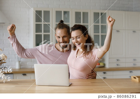 Overjoyed bonding young family couple celebrating internet success. Overjoyed bonding young family couple celebrating internet success. 86086291
