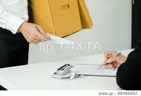 Desperately fired man office worker employee hands her employer her resignation letter and packs her belongings in a cardboard box concept dismissal and unemployment 86086892