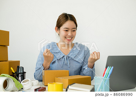 Young Asian woman business owner with many parcel boxes on the table happy online sales job, use the laptop, get an order from customers, take notes, and make arrangements for delivery by post Young Asian woman business owner with many parcel boxes on the table happy online sales job, use the laptop, get an order from customers, take notes, and make arrangements for delivery by post 86086990