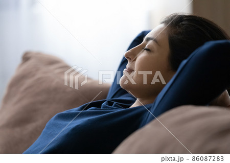 Peaceful happy young Indian woman resting on cozy sofa. Peaceful happy young Indian woman resting on cozy sofa. 86087283