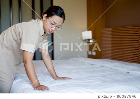 Housekeeper cleaning hotel rooms, changing mattresses, ready to accommodate arriving guests 86087946