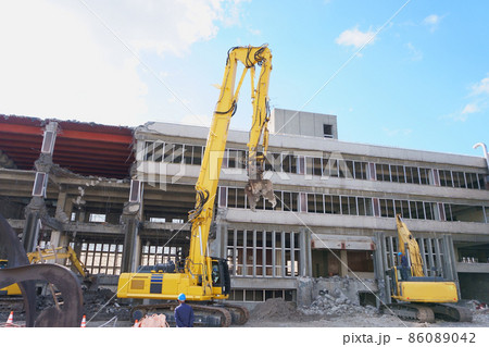 老朽化した公共建造物の解体作業をする重機 86089042