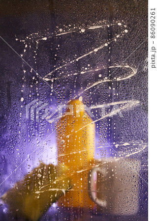 Close-up of household cleaning products and kitchen accessories. On a dark lilac background. View through dirty glass. The concept of cleaning the house, washing dishes. High quality photo 86090261