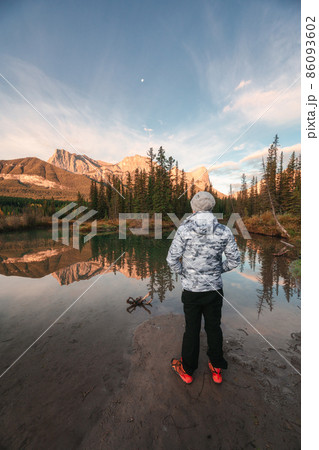 Man traveler standing enjoy the scenery of Three Sisters Mountains reflection on river in autumn at morning 86093602