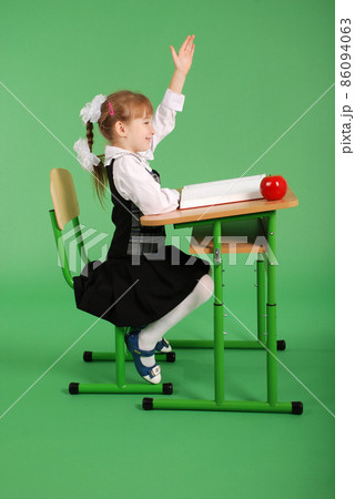 Girl in a school uniform sitting at a desk Girl in a school uniform sitting at a desk 86094063