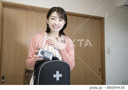 笑顔で非常用持出袋の中身を確認する女性 86094436