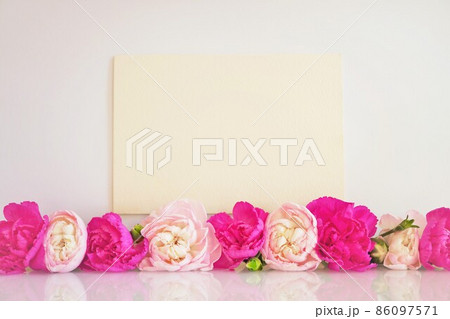 一列に並んだ赤とピンク色のカーネーションの花を添えた母の日のイメージのメッセージカードのモックアップ 86097571