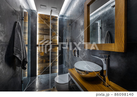Stylish dark bathroom interior with shower. Tiles imitating wood on the floor and on the wall Stylish dark bathroom interior with shower. Tiles imitating wood on the floor and on the wall 86098140