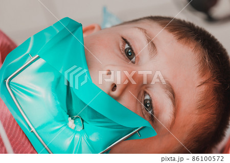 The dentist treats the child's tooth using a rubber dam. The dentist treats the child's tooth using a rubber dam. 86100572